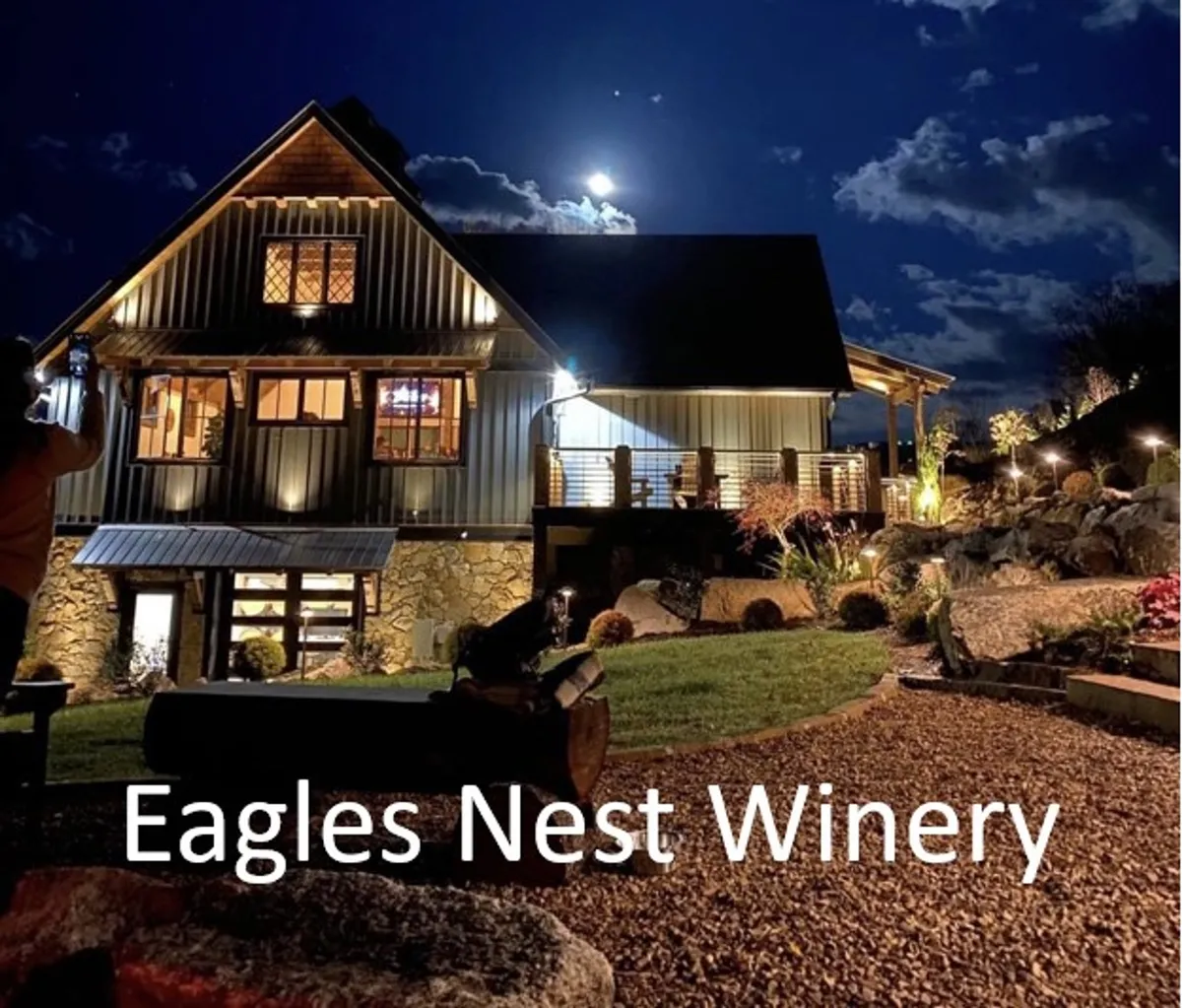 A nighttime view of the illuminated Eagles Nest Winery building set against a moonlit sky. The landscaped gardens and glowing architecture evoke an atmosphere of sophistication and leisure—perfect for wine tasting and evening gatherings.